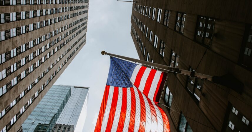 Bilden visar skyskrapor med amerikanska flaggan hängandes från fasaden