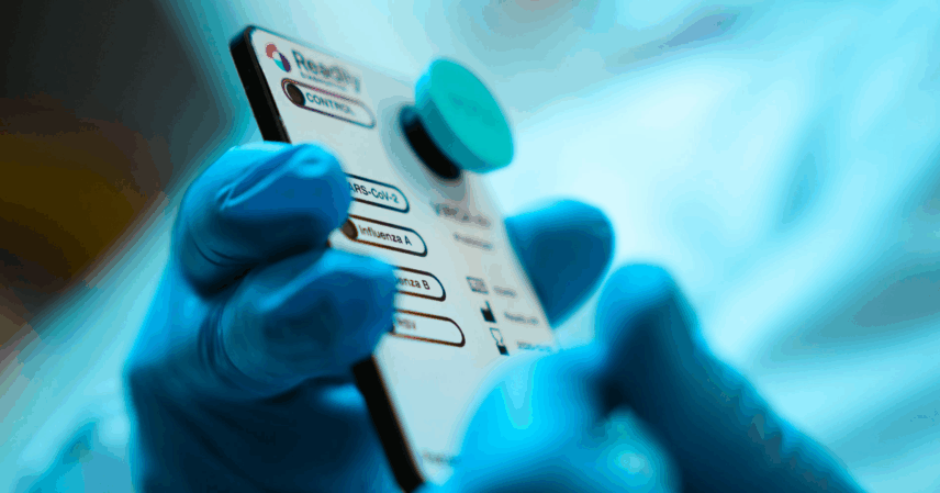 En hand med blå handske som håller en aparat.